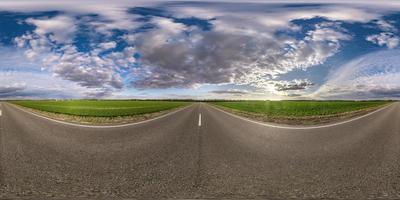 Panorama esférico completo sin costuras Vista angular de 360 grados en carretera asfaltada sin tráfico entre campos por la noche antes de la puesta del sol con cielo nublado. Panorama 360 en proyección equirrectangular, contenido vr ar foto