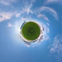 Little planet transformation of spherical panorama 360 degrees. Spherical abstract aerial view in field with awesome beautiful clouds. Curvature of space. photo