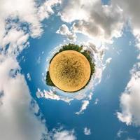 Little planet transformation of spherical panorama 360 degrees. Spherical abstract aerial view in field in nice evening with awesome beautiful clouds. Curvature of space. photo