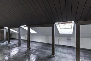 interior vacío de la habitación de buhardilla sin amueblar con columnas de madera y suelo de hormigón húmedo en el nivel del techo en color negro y de estilo completo foto