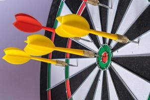 Red and yellow dart arrows hitting in the target center of dartboard. Success hitting target aim goal achievement concept photo