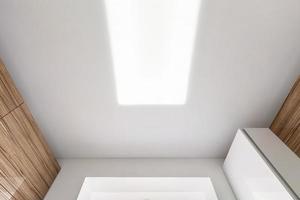 looking up on suspended ceiling with halogen spots lamps and drywall construction in empty room in apartment or house. Stretch ceiling white and complex shape. photo