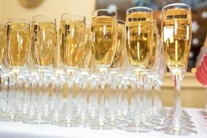 lot of blurred glasses with champagne on the reception party table on light background photo