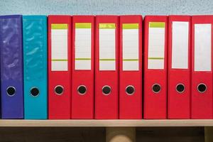 row of folders for papers and documentation on a shelf in the office photo