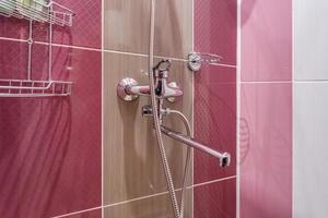 water tap sink with faucet in expensive loft bathroom. detail of a corner shower cabin with wall mount shower attachment on pink wall photo