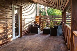 interior de la terraza de la sala vacía en la casa de vacaciones de un pueblo de madera con lámparas y sillas antiguas foto