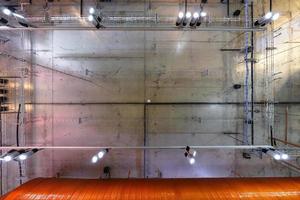 gray concrete ceiling with halogen spots and edison lamps in loft office room with air conditioning and orange ventilation pipe. looking up photo