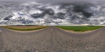 full seamless spherical hdr panorama 360 degrees angle view on old no traffic asphalt road among fields with black rain clouds before storm in equirectangular projection, VR AR virtual reality content photo