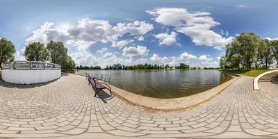 full seamless spherical hdri panorama 360 degrees angle view on concrete pier of huge lake or river in sunny summer day among the bushes of small town in equirectangular projection, VR content photo