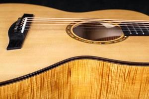 textura de madera de la cubierta inferior de guitarra acústica de seis cuerdas sobre fondo negro. forma de guitarra foto