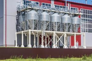 ascensor de granero moderno. silos de plata en la planta de procesamiento y fabricación de productos agrícolas para el procesamiento, secado, limpieza y almacenamiento de productos agrícolas, harina, cereales y granos. foto