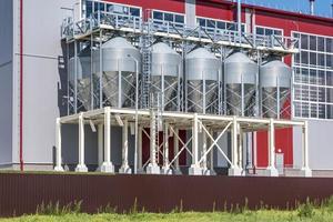 Modern Granary elevator. Silver silos on agro-processing and manufacturing plant for processing drying cleaning and storage of agricultural products, flour, cereals and grain. photo