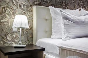 lámpara de noche con pantalla en las mesitas de noche cerca de la cama doble con almohadas en el interior del dormitorio moderno foto