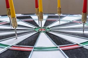 Red and yellow dart arrows hitting in the target center of dartboard. Success hitting target aim goal achievement concept photo