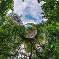 Little planet transformation of spherical panorama 360 degrees. Spherical abstract aerial view in field with awesome beautiful clouds. Curvature of space. photo