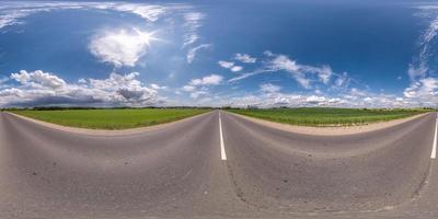 vista de ángulo de 360 grados de panorama hdri esférico completo sin tráfico en carretera asfaltada entre campos con cielo azul claro en proyección equirectangular, contenido vr ar foto