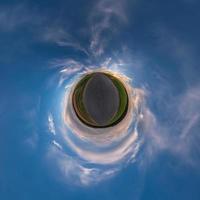 Little planet transformation of spherical panorama 360 degrees. Spherical abstract aerial view in field with awesome beautiful clouds. Curvature of space. photo