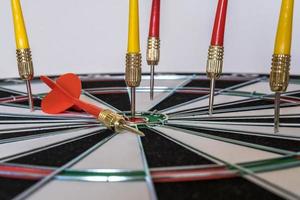 Red and yellow dart arrows hitting in the target center of dartboard. Success hitting target aim goal achievement concept photo