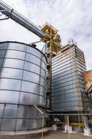 Modern Granary elevator. Silver silos on agro-processing and manufacturing plant for processing drying cleaning and storage of agricultural products, flour, cereals and grain. photo