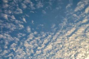 Blue sky background with tiny curly rolling clouds in the evening. Clearing day and Good windy weather photo