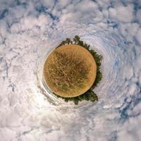 pequeño planeta transformación de panorama esférico 360 grados. vista aérea abstracta esférica en el campo en una agradable velada con impresionantes nubes hermosas. curvatura del espacio. foto