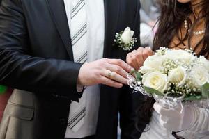 groom embraces the bride with wedding bouquet. rings on the hands of newly-married couple. bride put her hands on the shoulders of the bridegroom. photo