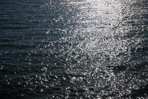 Sea water surface with ripple and sun reflection sparkles photo