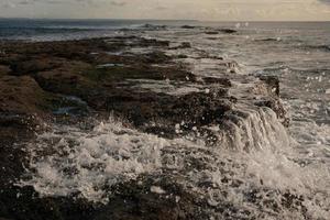 salpicando olas en la playa de rocas foto