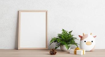 Empty photo frame mockup on wooden table with cow doll plant pine cone and gift box. Art and decoration concept. 3D illustration rendering