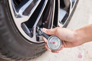 Close-Up Of Hand holding pressure gauge for car tyre pressure measurement photo