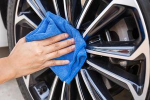 mano con paño de microfibra azul limpiando la rueda del coche. foto