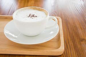 cappuccino in a white cup on a wooden plate on table photo