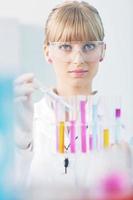 female researcher holding up a test tube in lab photo