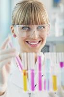 female researcher holding up a test tube in lab photo