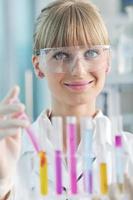 female researcher holding up a test tube in lab photo