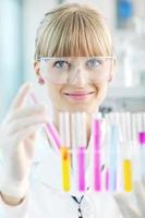 female researcher holding up a test tube in lab photo