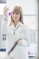 female researcher holding up a test tube in lab photo