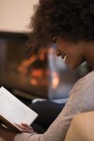 black woman at home reading book photo