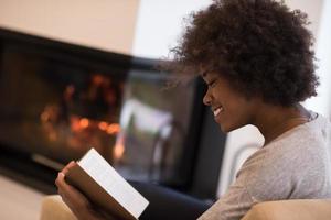 black woman at home reading book photo