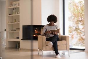 black woman at home reading book photo