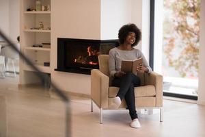 black woman at home reading book photo