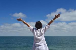 mujer joven feliz con los brazos extendidos al cielo foto