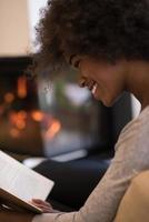 black woman at home reading book photo