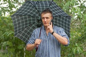 hombre con paraguas y teléfono móvil foto