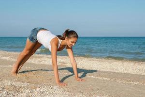 young woman practicing yoga or fitness at seashore photo