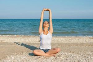 mujer joven practicando yoga o fitness en la orilla del mar foto