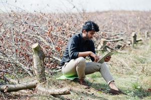South asian agronomist farmer with clipboard inspecting cut trees in the farm garden. Agriculture production concept.