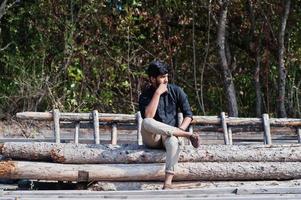 South asian agronomist farmer sitting on woods at farm. Agriculture production concept. photo