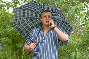 hombre con paraguas y teléfono móvil foto