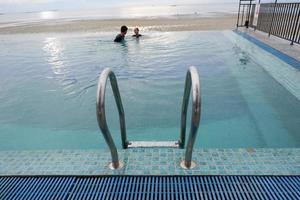 Papua, Indonesia - October 10, 2021. People swimming in the pool near the sea photo